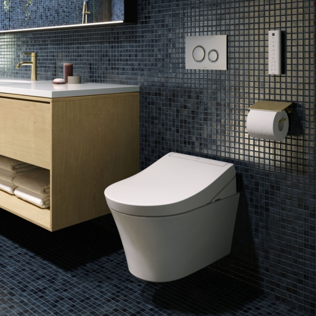 Close up image of the TOTO Washlet RG Rimless Wall Hung Toilet mounted on a black tiled bathroom wall, next to a wooden wall-mounted vanity unit and below a chrome dual flush plate
